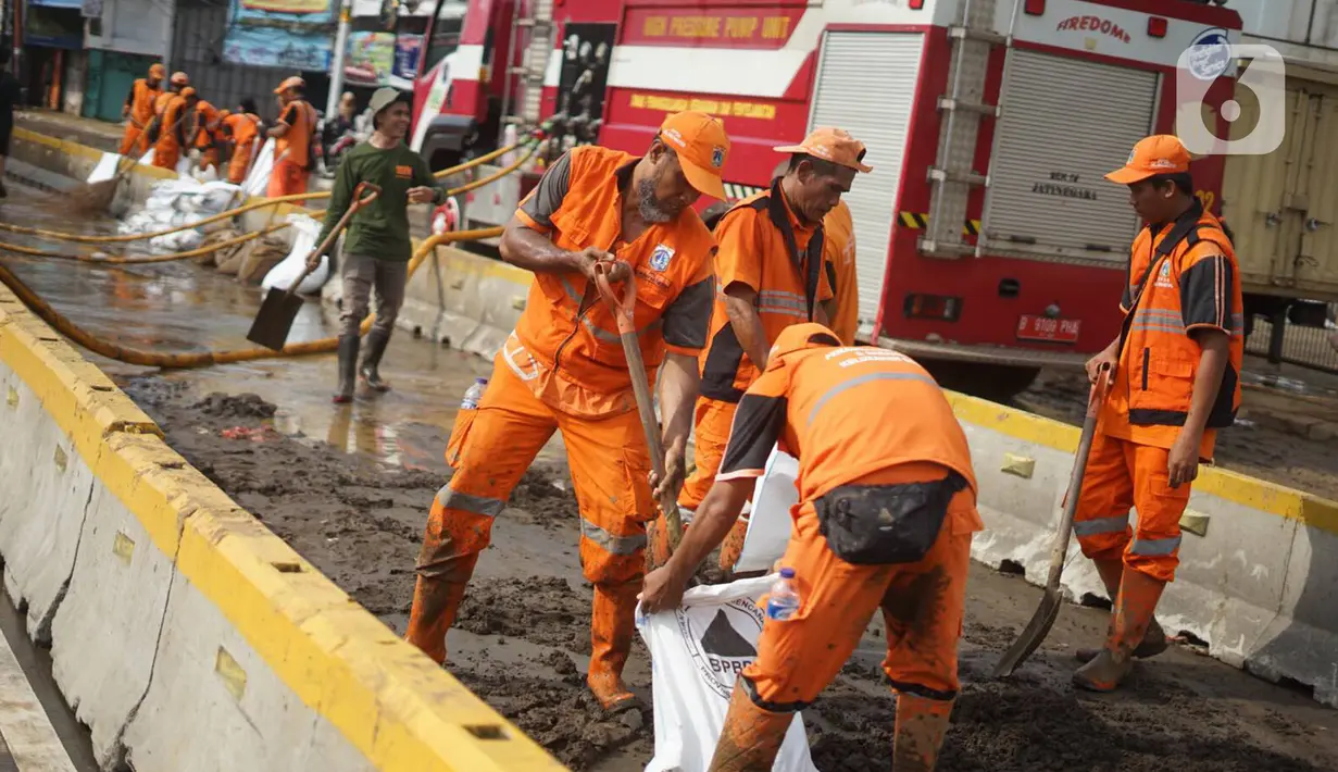 Petugas Penanganan Prasaran dan Sarana Umum (PPSU) membersihkan lumpur yang mengendap di sepanjang Jalan Jatinegara Barat, Kampung Melayu, Jakarta Timur, Kamis (2/1/2020). Petugas melakukan bersih-bersih menyusul mulai surutnya banjir di kawasan tersebut. (Liputan6.com/Immanuel Antonius)