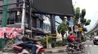 Pengendara motor melintas di depan sebuah videotron di simpang Jalan Iskandarsyah, Jakarta Selatan, Minggu (2/10). Garis polisi terpasang terkait insiden videotron yang memutar video porno pada Jumat, 30 September 2016 lalu. (Liputan6.com/Helmi Afandi)