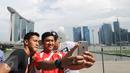 Para penggawa Garuda Muda bersantai sejenak usai melaksanakan ibadah salat Jumat di Masjid Sultan, Bugis, Singapura (5/6). Yandi Sofyan, M Natshir dan Agung Prasetyo (kiri-kanan) ber-selfie berlatar Marina Bay Sand. (Liputan6.com/Helmi Fithriansyah)