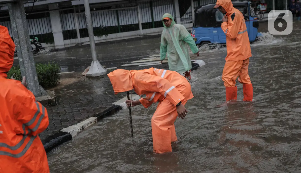 Petugas memeriksa genangan air di Jalan Medan Merdeka Timur, Jakarta, Jumat (24/1/2020). Hujan deras yang mengguyur Jakarta sejak pagi tadi mengakibatkan genangan air di Jalan Medan Merdeka Timur. (Liputan6.com/Faizal Fanani)