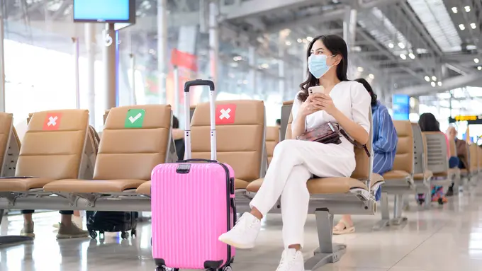 perempuan di bandara traveling memakai masker