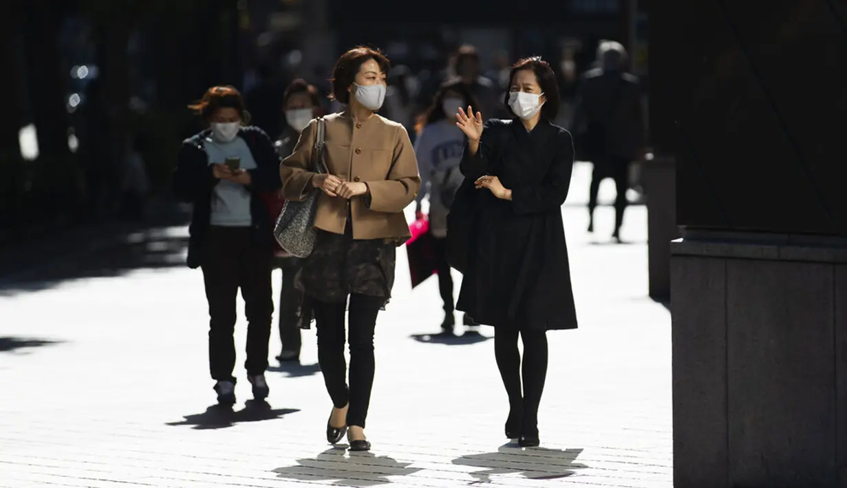 Wanita dengan masker wajah berjalan di Tokyo, Jepang, Jumat (16/10/2020). Ibu Kota Jepang itu mengonfirmasi lebih dari 180 kasus virus corona COVID-19 baru pada hari Jumat. (AP Photo/Hiro Komae)