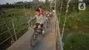 Anak-anak bersepeda melintasi jembatan gantung di Kelurahan Curug, Bojongsari, Kota Depok, Jawa Barat, Senin (24/8/2020). Setiap sore, warga sekitar bermain di jembatan tersebut sambil menikmati matahari tenggelam. (merdeka.com/Dwi Narwoko)