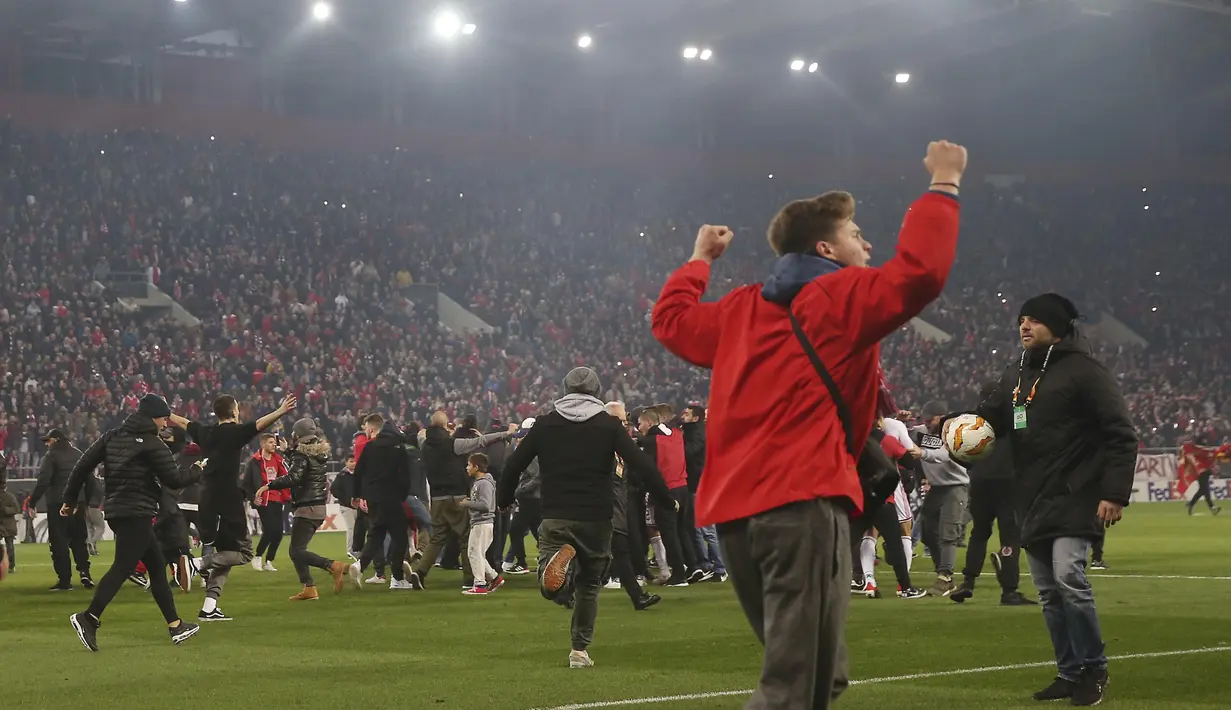 Para suporter Olympiakos turun ke lapangan merayakan kemenangan atas AC Milan pada laga Europa di Stadion Georgios Karaiskakis, Athena, Kamis (13/12). Olympiakos menang 3-1 atas AC Milan. (AP/Thanassis Stavrakis)