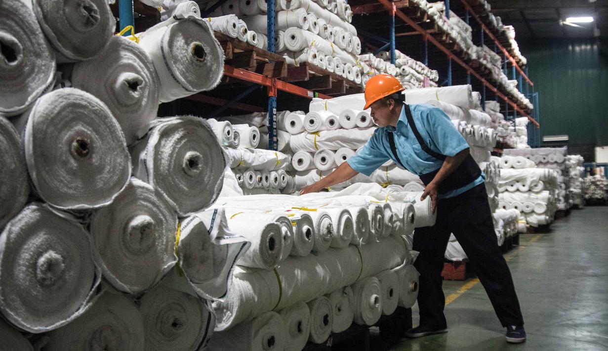 Seorang pekerja menyusun gulungan kain di Trisula Textile Industries, Cimahi, Jawa Barat pada Rabu 22 April 2026, ketika para produsen tekstil menghadapi biaya yang lebih tinggi akibat melonjaknya harga bahan baku petrokimia yang terkait dengan kenaikan harga minyak global. Industri dan produk tekstil (TPT) di Indonesia sedang menghadapi tekanan berat akibat lonjakan harga bahan baku berbasis petrokimia. (Timur MATAHARI/AFP)
