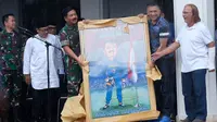 Marsekal Hadi Tjahjono menerima karikatur dari Wakil Ketua Umum PSSI, Iwan Budianto, di Bali Kota Malang, Minggu (3/3/2019). (Bola.com/Iwan Setiawan)