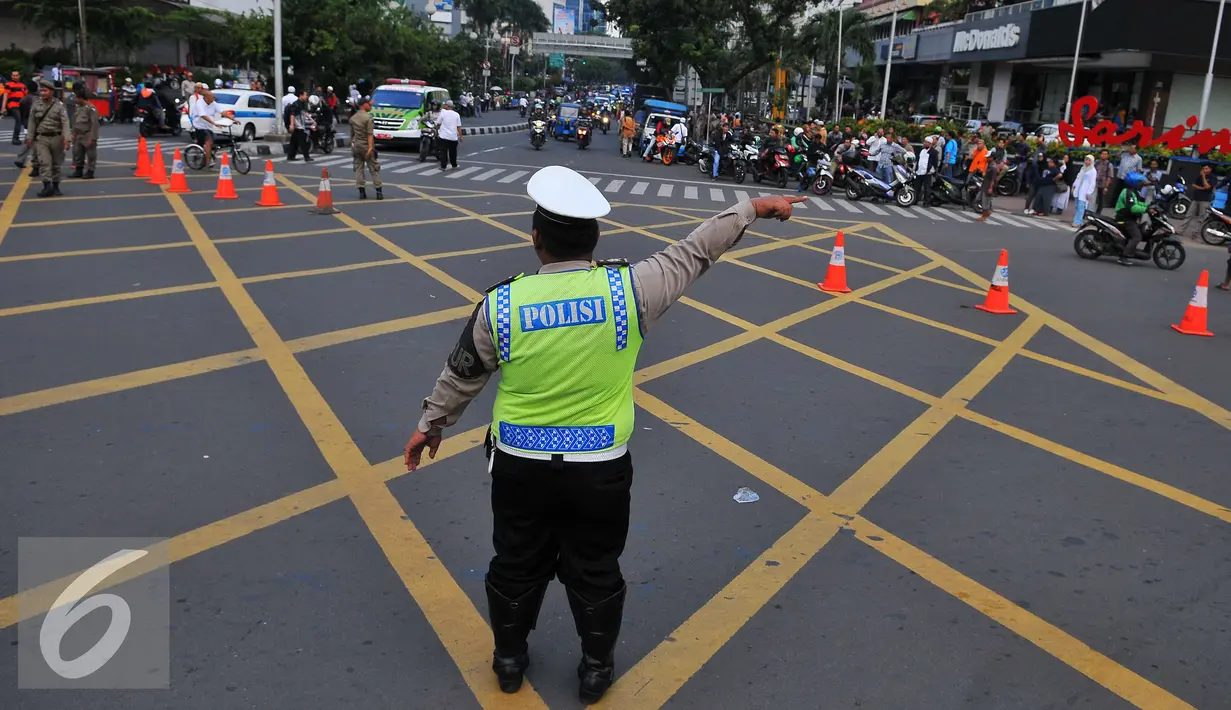 Seorang petugas polisi mengalihkan arus di kawasan Sarinah, Jakarta, Jumat (4/11). Pengalihan ini dilakukan karena aksi 4 November yang memadati tiga titik, yaitu di kantor Bareskrim Polri Balai Kota DKI, dan Istana Negara. (Liputan6.com/Angga Yuniar)