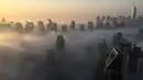 Suasana saat kabut pagi hari menyelimuti gedung-gedung pencakar langit di Kota Dubai, Uni Emirat Arab, Senin (5/12). Ketika udara dingin pada malam hari bertemu dengan pagi yang panas dan lembab, kabut terbentuk pada dini hari. (AFP/Rene Slama)