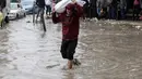 Kondisi tersebut semakin memperburuk krisis kemanusiaan yang dihadapi ratusan ribu pengungsi di Gaza. Tampak dalam foto, seorang pria membawa karung sambil berjalan di tengah banjir di kamp darurat yang menampung warga Palestina yang terlantar setelah hujan deras di Kota Gaza pada Selasa 25 November 2025. (Omar AL-QATTAA/AFP)
