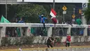 Mahasiswa mengibarkan bendera Merah Putih saat demonstrasi menolak pengesahan RUU KUHP dan revisi UU KPK di depan Gedung DPR, Jakarta, Selasa (24/9/2019). Mahasiswa lari tunggang langgang setelah aparat kepolisian menembakkan gas air mata dan water cannon. (Liputan6.com/JohanTallo)