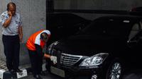 Petugas memasang pelat mobil baru di mobil dinas Menteri Perhubungan yang baru di Kemenhub, Jakarta, (27/10/2014). (Liputan6.com/Faizal Fanani) 