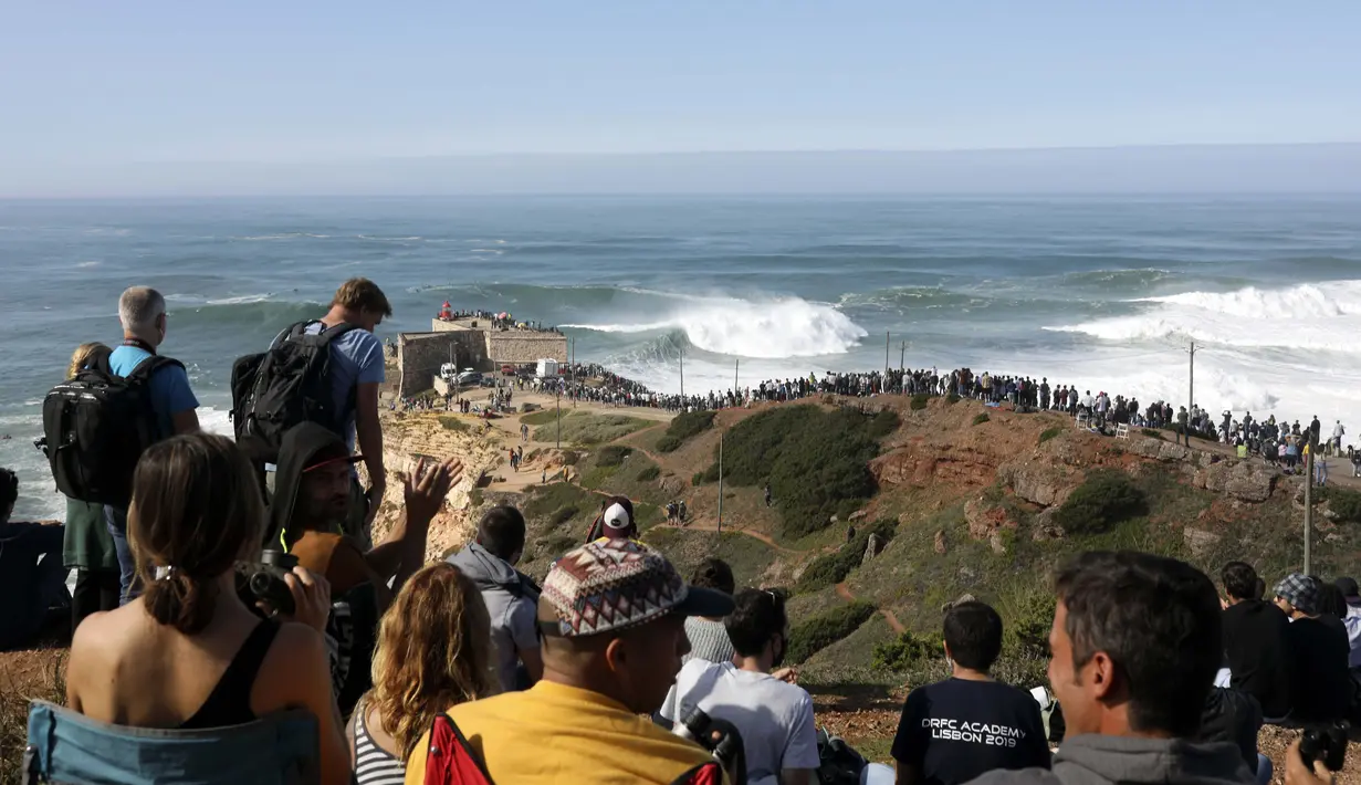Orang-orang berkumpul di sepanjang puncak tebing untuk menyaksikan sesi selancar derek di Praia do Norte atau Pantai Utara di Nazare, Portugal, Kamis (29/10/2020). (AP Photo/Pedro Rocha)