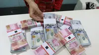 Teller menunjukkan mata uang rupiah dan dolar di Bank Mandiri, Jakarta, Kamis (10/1). Hingga hari ini, US$ 1 dibanderol Rp 14.020. Rupiah menguat 0,71% dibandingkan posisi penutupan perdagangan hari sebelumnya. (Liputan6.com/Angga Yuniar)