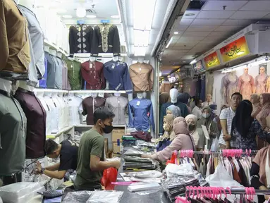 Calon pembeli memilih baju di Pasar Tanah Abang, Jakarta, (28/3/2022). Sepekan menjalang bulan suci Ramadan, Pasar Tanah Abang mulai dipadati pembeli yang hendak berbelanja untuk kebutuhan bulan puasa. (Liputan6.com/Herman Zakharia)