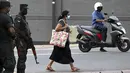 Seorang pejalan kaki melewati tentara yang berjaga di sepanjang jalan di Kolombo pada Sabtu (2/4/2022). Pasukan yang dipersenjatai dengan senapan serbu otomatis dikerahkan di Sri Lanka untuk mengendalikan massa, beberapa jam setelah presiden menyatakan keadaan darurat. (KODIKARA / AFP)