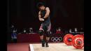Atlet angkat besi asal Indonesia Rahmat Erwin Abdullah menunjukkan ototnya kepada penonton usai berhasil meraih medali perunggu dari cabang angkat besi 73kg putra Olimpiade Tokyo 2020, Rabu (28/7/2021). (Foto: AP/Luca Bruno)