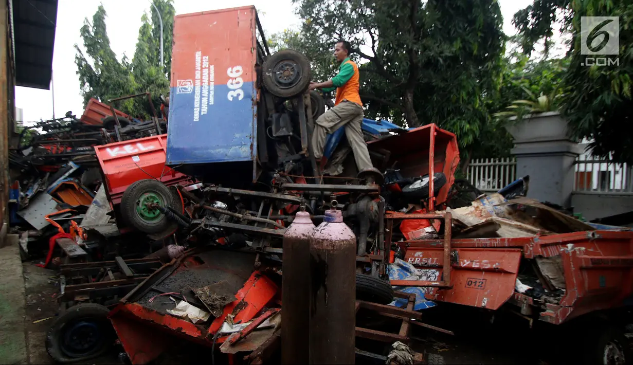 Petugas melakukan pengecekan bangkai armada truk sampah di Kantor Suku Dinas Lingkungan Hidup, Jakarta Barat, Selasa (27/3). Penumpukan armada tersebut dikarenakan kendaraan sudah tidak layak pakai. (Liputan6.com/JohanTallo)
