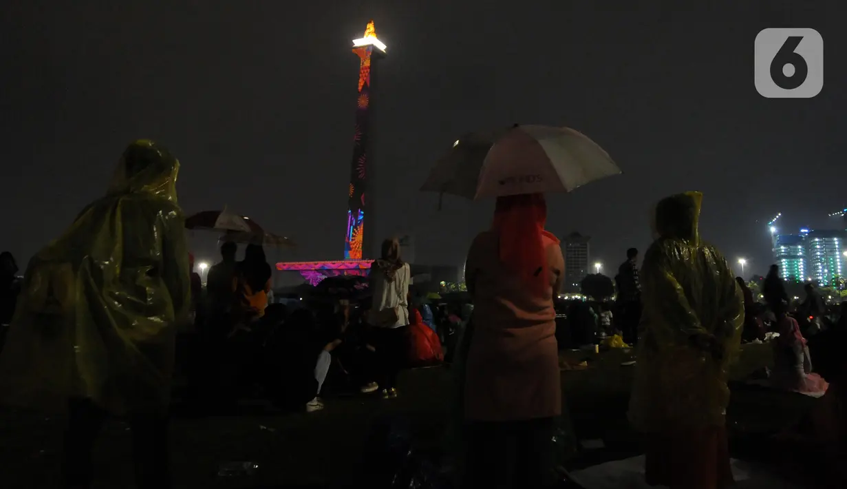 Pengunjung menyaksikan penampilan video mapping saat malam pergantian tahun di kawasan Monumen Nasional, Jakarta, Selasa (31/12/2019). Penampilan video mapping mewarnai kemeriahan malam pergantian tahun baru di kawasan Monumen Nasional, Jakarta. (Liputan6.com/Helmi Fithriansyah)