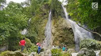 Sejumlah wisatawan menikmati air terjun dengan berfoto di Air Terjun Sri Gethuk, Kabupaten Gunungkidul, Yogyakarta, Sabtu (11/11). Wisatawan harus menempuh perjalanan melintasi Sungai Oya sepanjang 400 meter. (Liputan6.com/Herman Zakharia)