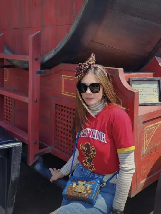 Wulan beserta tiga anak dan kekasihnya juga mengunjungi Universal Studio Jepang. Dalam potret tersebut, Wulan mengenakan tshirt Gryffindor merah dengan inner lengan panjang dipadukan celana denimnya.  Credit: Instagram (@wulanguritno)