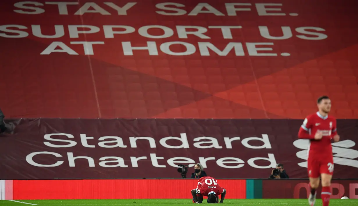 Penyerang Liverpool, Sadio Mane mencium lapangan saat berselebrasi usai mencetak gol ke gawang Arsenal pada pekan ketiga Liga Inggris di Anfield, Selasa dinihari WIB (29/9/2020). Tertinggal lebih dulu, Liverpool mampu membungkam Arsenal dengan skor 3-1. (Paul Ellis / Pool via AP)