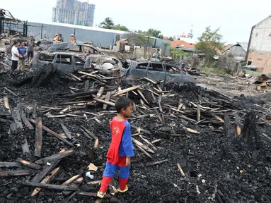 Seorang bocah berdiri di atas puing-puing kebakaran yang menghanguskan lapak kayu di kawasan Rawa Buaya, Jakarta Barat, Rabu (4/1). Banyak warga yang terlihat mengumpulkan apa yang bisa diambil dari sisa puing bangunan itu. (Liputan6.com/Angga Yuniar)