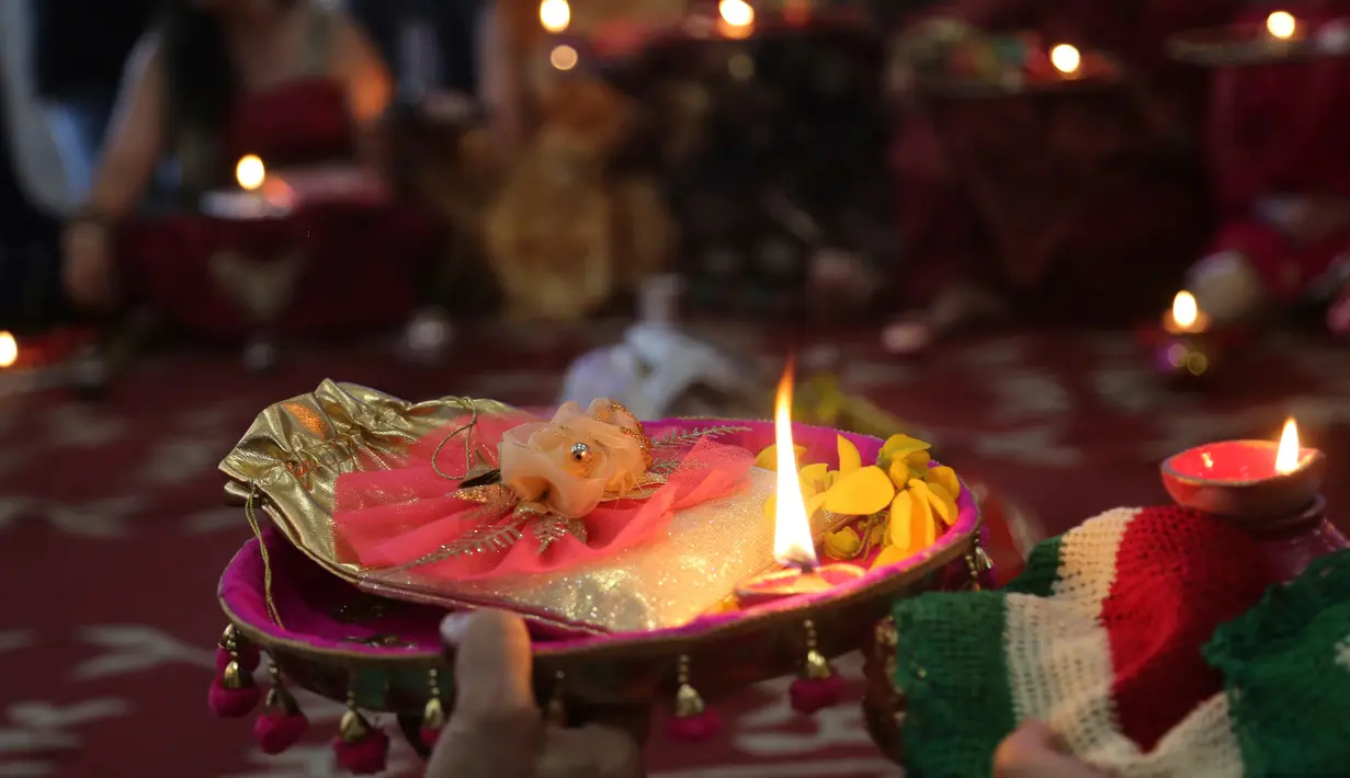 Seorang wanita Hindu yang sudah menikah melakukan ritual festival Karva Chauth di Ahmadabad,  Kamis (17/10/2019). Selama festival Karva Chauth, wanita-wanita yang sudah menikah di India berpuasa sepanjang hari dan memohon umur panjang serta keselamatan untuk suami mereka. (AP/Ajit Solanki)