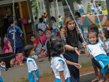 Pendiri Yayasan Pansophia Nusantara, Millie Lukito bermain bersama anak-anak Pendidikan anak usia dini (PAUD) Cahaya Permata Indonesia (CPI) di Rusunawa Marunda, Jakarta Utara, Jumat (30/11). (Liputan6.com/Faizal Fanani)