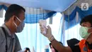 Petugas mengecek suhu penumpang yang menaiki kapal ferry saat pemeriksaan dokumen di Pelabuhan Merak, Banten, Senin (18/5/2020). Penumpang harus memenuhi sejumlah persyaratan ketat mencakup standar kesehatan dan verifikasi dokumen guna memutus rantai penyebaran COVID-19. (Liputan6.com/Angga Yuniar)
