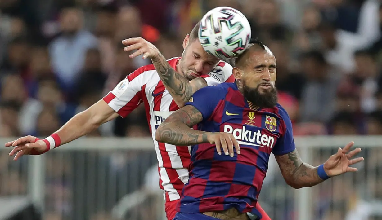 Gelandang Barcelona, Arturo Vidal melompat saat berebut bola dengan pemain Atletico Madrid, Saul pada laga semifinal Piala Super Spanyol di King Abdullah Sports City, Jeddah, Kamis (9/1/2020). Barcelona harus menjalani pertandingan yang dramatis saat kalah 2-3 dari Atletico Madrid. (AP/Hassan Ammar)