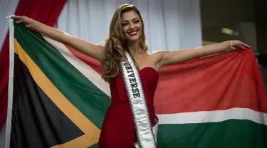 Miss Universe 2017 Demi-Leigh Nel-Peters berpose dengan bendera Afrika Selatan saat tiba di Bandara Internasional OR Tambo di Johannesburg (24/1). Untuk pertama kalinya setelah dinobatkan Demi Leigh baru pulang ke Afrika Selatan. (AFP Photo/Gulshan Khan)