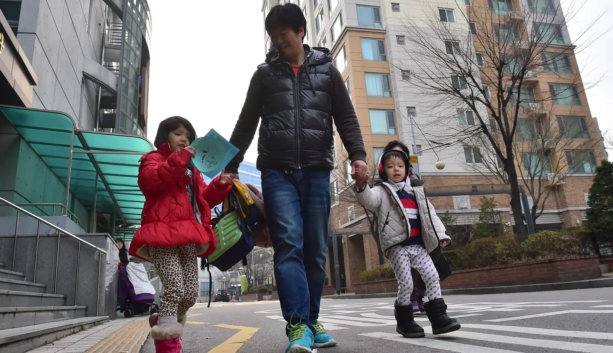 Gambar ini diambil pada 22 Desember 2015 menunjukkan seorang ayah dari Korea Selatan, Kim Jin-Sung (tengah) berjalan bersama putrinya Na-Eun dan Won-Woo pulang dari pusat penitipan anak di Seoul. (AFP PHOTO/JU)