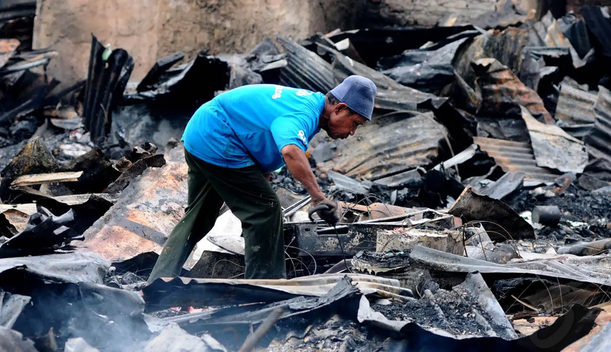Seorang lelaki terlihat berusaha mencari harta benda yang masih bisa diselamatkan dari kebakaran yang melanda tempat tinggalnya. (Liputan6.com/Andrian M Tunay)
