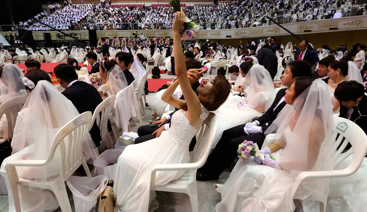 Seorang wanita berselfie saat mengikuti pernikahan massal di Pusat Perdamaian Cheong Shim di Gapyeong, Korea Selatan, (7/9). Sebanyak 4.000 pasangan Korea Selatan dan asing ikut serta dalam acara ini. (AP Photo / Ahn Young-joon)