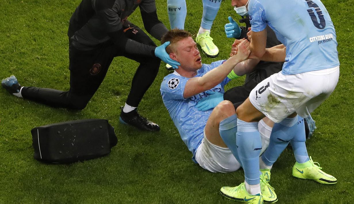 Kevin De Bruyne (tengah) dibantu untuk bangun setelah menjalani perawatan karena tabrakan dengan Antonio Rudiger selama pertandingan final Liga Champions antara Manchester City dan Chelsea di Stadion Dragao di Porto, Portugal, Sabtu (29/05/2021) atau Minggu dini hari WIB. (Foto: AP/Pool/Susana Vera)
