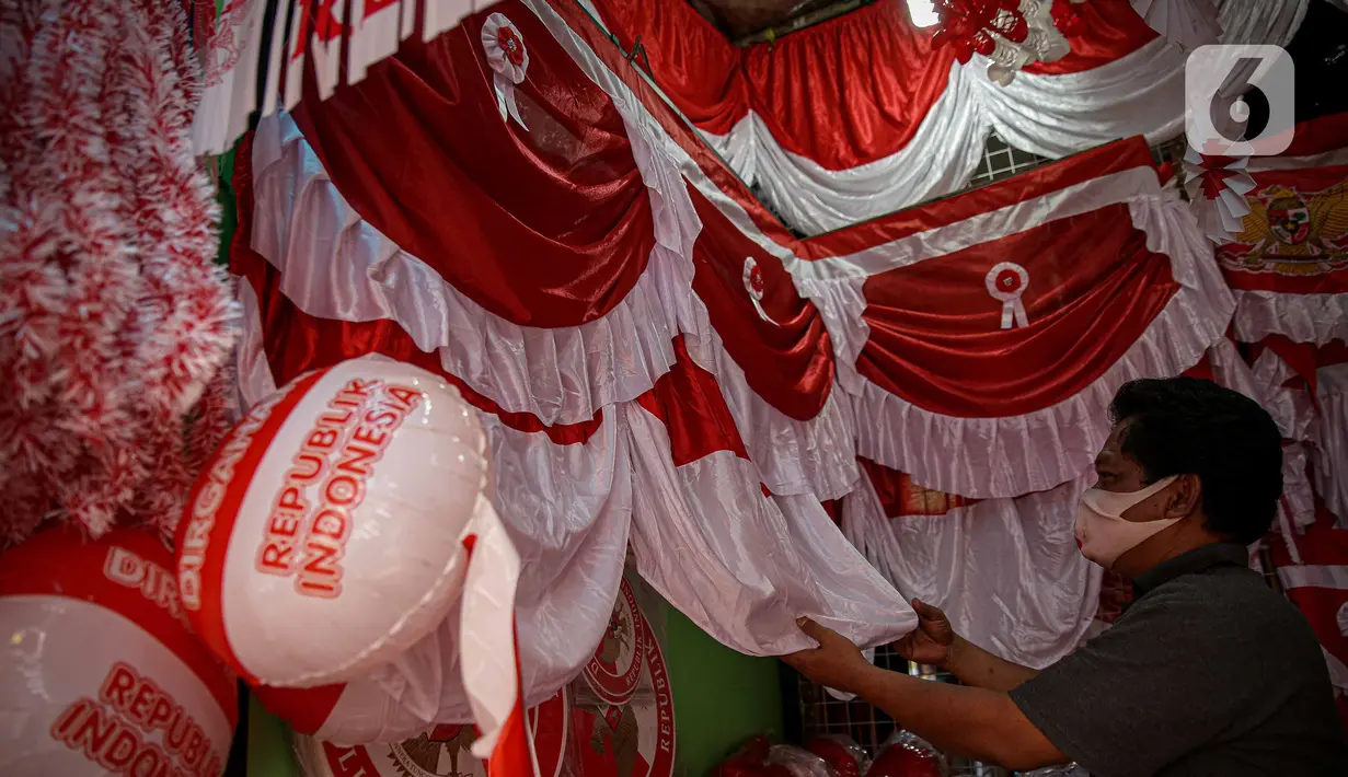 Pedagang merapikan pernak pernik HUT Republik Indonesia di Pasar Jatinegara, Jakarta, Selasa (10/8/2021). Dua tahun pandemi Covid-19 berjalan, penjual pernak pernik hingga bendera merah putih  turun 50-70 persen serta daya beli masyarakat pun turun karena PPKM Darurat. (Liputan6.com/Faizal Fanani)