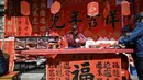 Seorang kaligrafer menulis kuplet musim semi, semacam dekorasi Tahun Baru Imlek, jelang dimulainya Tahun Baru Imlek di sebuah kios di Foshan, Provinsi Guangdong, China, 18 Januari. Dua baris kuplet yang biasanya terdiri dari tujuh atau sembilan karakter ditempelkan pada kedua sisi ambang pintu. (Giok Gao/AFP)
