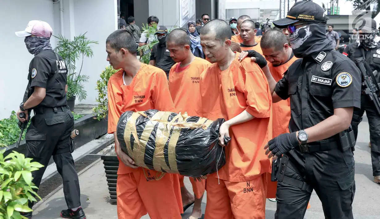 Petugas membawa para tersangka seusai rilis penyelundupan narkoba jaringan Malaysia di Gedung BNN, Jakarta, Selasa (16/10). BNN berhasil menggagalkan penyelundupan 14,6 kg sabu dan 63.573 ekstasi dari 4 kasus berbeda. (Liputan6.com/Immanuel Antonius)