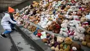 Seorang siswa meletakkan satu boneka beruang atau Teddy Bears di tangga Concert Hall, Berlin, Kamis (15/3). Kelompok bantuan kemanusiaan World Vision melakukan aksi pengumpulan 740 boneka beruang. (AFP PHOTO/Odd ANDERSEN)