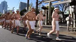 Penganut Shinto melakukan pemanasan sebelum memasuki kolam renang es untuk berdoa dan memurnikan tubuh dan jiwa dalam ritual Upacara Penyucian di Tokyo, Minggu (10/01/2016). (AFP Photo/ Toru Yamanaka)