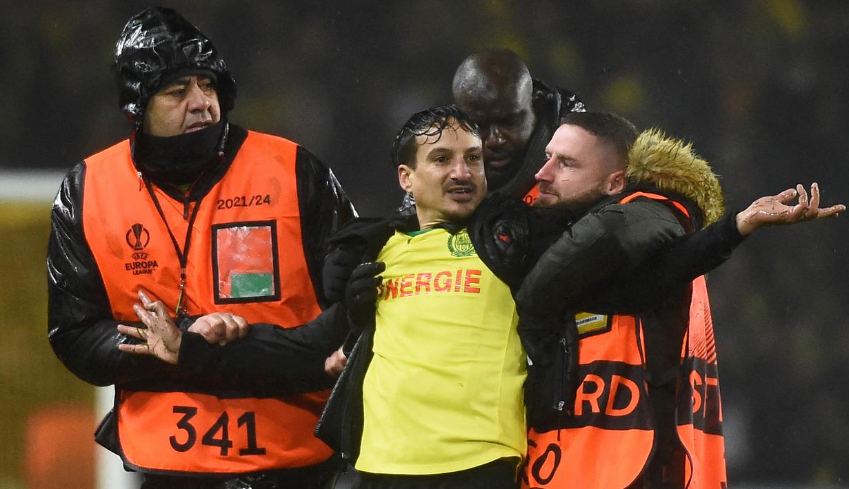 Pihak keamanan menangkap seorang suporter yang masuk ke lapangan dalam laga leg kedua play-off babak Liga Europa 2022/2023 antara Nantes melawan Juventus yang berlangsung di Stade de la Beaujoire, Jumat (24/2/2023). (AFP/Sebastien Salom-Gomis)