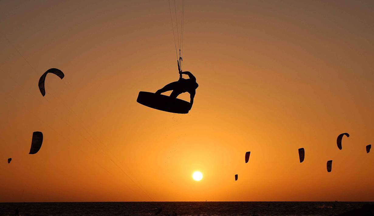 Warga Israel berolahraga Selancar Layang (kitesurfing) saat matahari terbenam di lepas pantai Tel Aviv, pada 21 Oktober 2025. (JACK GUEZ/AFP)