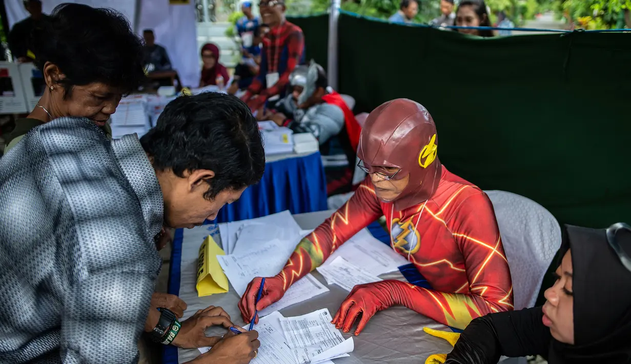 Petugas Kelompok Penyelenggara Pemungutan Suara (KPPS) berkostum superhero The Flash mendata warga yang akan mencoblos dalam Pemilu 2019 di sebuah TPS di Surabaya, Jawa Timur, Rabu (17/4). Ada sembilan petugas KPPS yang mengenakan kostum superhero di TPS ini. (Juni Kriswanto/AFP)