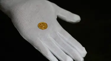 Seorang karyawan Dix Noonan Webb menunjukkan koin Romawi kuno di London, Inggris (28/5/2019). Koin emas ini berasal dari tahun 293-296 M yang ditemukan di sebuah lapangan di Kent, Inggris. (AP Photo/Kirsty Wigglesworth)