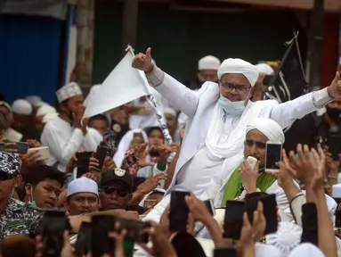 Rizieq Shihab menyapa massa pendukungnya saat tiba di kediamannya di Jalan Petamburan, Jakarta, Selasa (10/11/2020). Rizieq Shihab tiba di kediamannya usai pulang dari Arab Saudi. (merdeka.com/Imam Buhori)