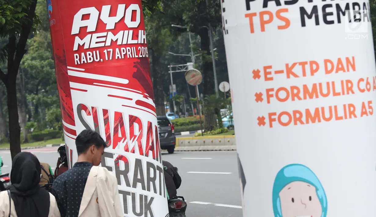 Pejalan kaki melintas di sisi media sosialisasi pelaksanaan Pemilu Serentak 2019 di depan kantor Kemenkominfo jalan Medan Merdeka Barat, Jakarta, Selasa (26/2). KPU menargetkan tingkat pemilih mencapai 77,5 persen. (Liputan6.com/Helmi Fithriansyah)