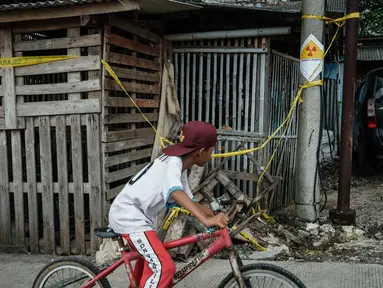 Sebuah stiker peringatan bertuliskan “Bahaya Radiasi” dengan catatan tulisan tangan yang menunjukkan “11,5 mikrosievert per jam” terlihat di salah satu tiang listrik di samping Kawasan Industri Modern Cikande, tempat isotop radioaktif Cesium-137  terdeteksi, di Sukatani, Banten pada 13 Oktober 2025. (Yasuyoshi CHIBA/AFP)