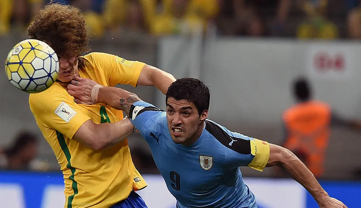 Striker Uruguay, Luis Suarez, berebut bola dengan bek Brasil, David Luiz, pada kualifikasi Piala Dunia 2018 di Recife, Brasil, Sabtu (26/3/2016) pagi WIB. Ini adalah comeback Suarez usai dihukum larangan bertanding 9 laga. (AFP/Vanderlei Almeida)