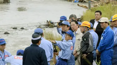 PM Shinzo Abe mendengarkan penjelasan petugas saat mengunjungi wilayah barat daya Jepang yang hancur akibat longsor dan banjir, Rabu (12/7). Abe berjanji pemerintah akan membantu pembangunan kembali di daerah itu segera. (Nozomi Endo/Kyodo News via AP)