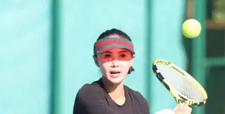 Yuni Shara tampil serba hitam memadukan long sleeve top, rok tenis dan sneakers putih. Topi tenis warna merah pun jadi statement pada penampilannya. @yunishara36.